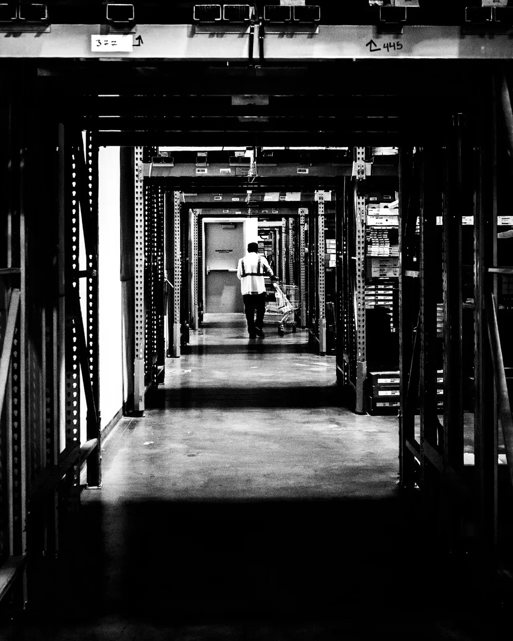 Allée d'entrepôt logistique aux rayonnages hauts en noir et blanc