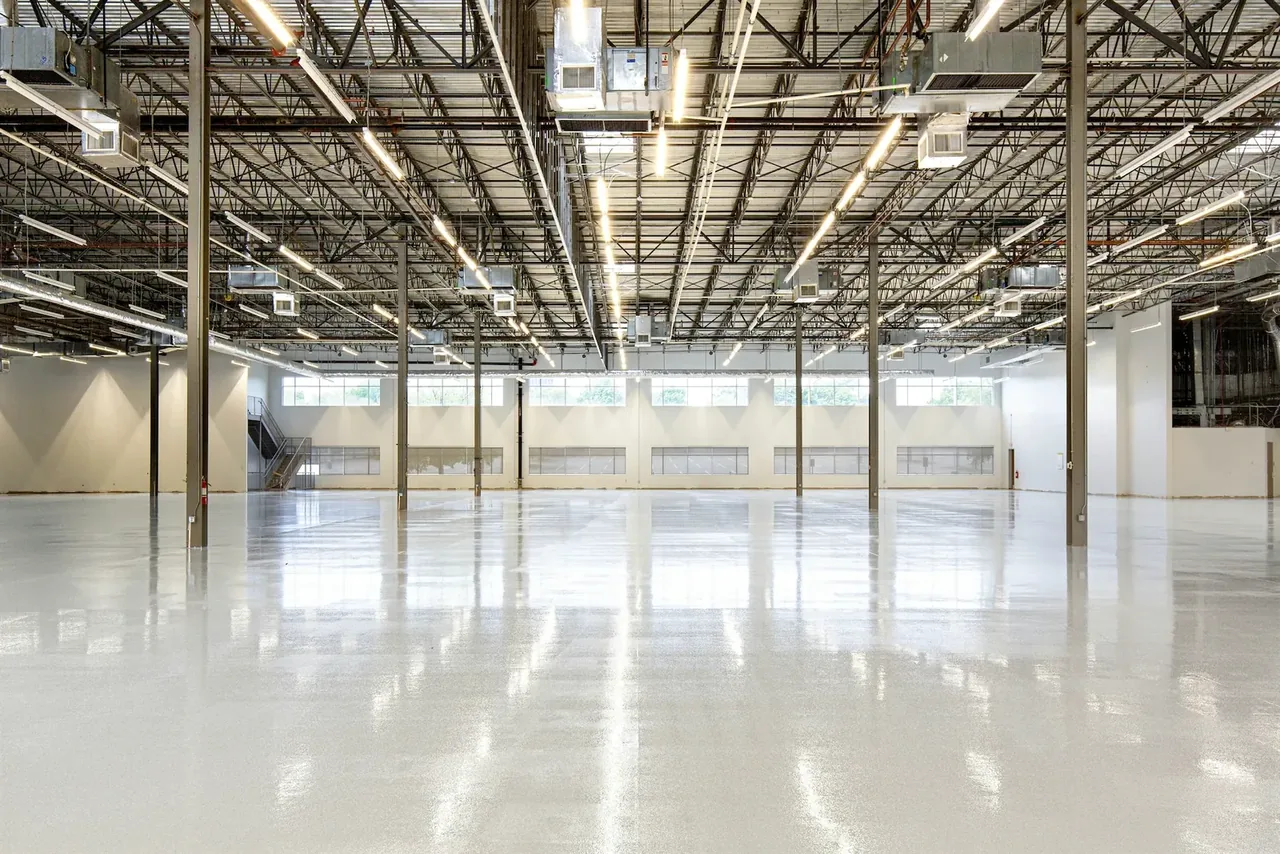 Sol béton résiné brillant dans un vaste hall industriel vide