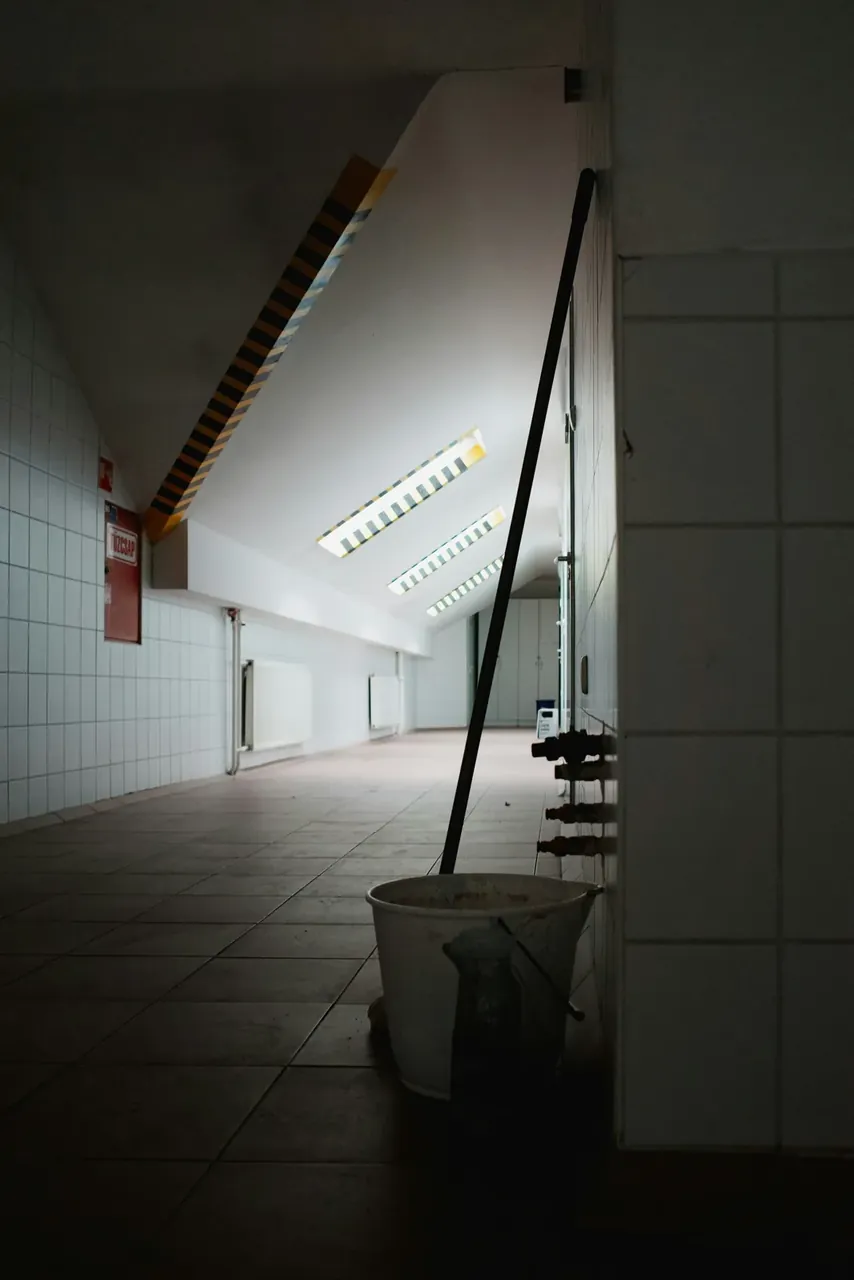 Seau de lavage et serpillère dans le couloir carrelé d'un établissement