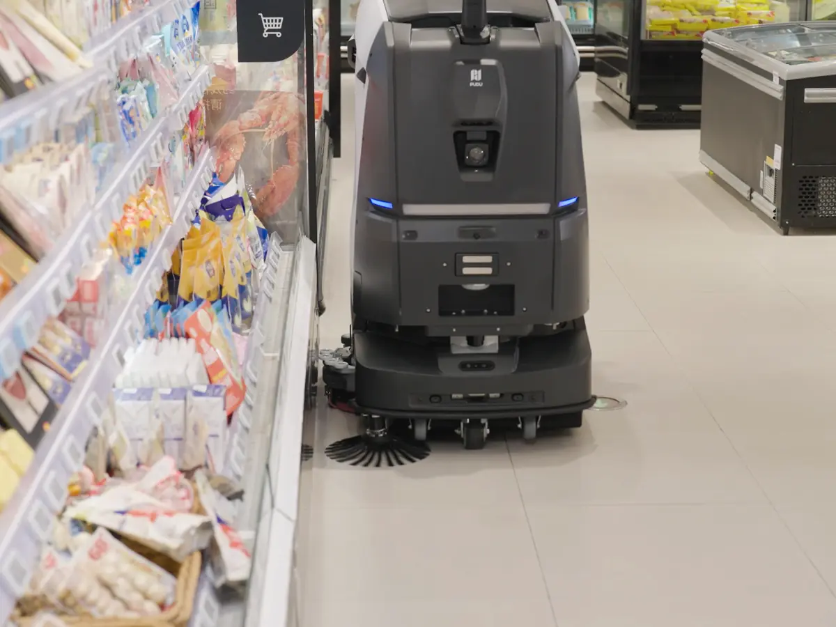 The extendable brush of the PUDU BG1 scrubbing along the base of a shelving unit