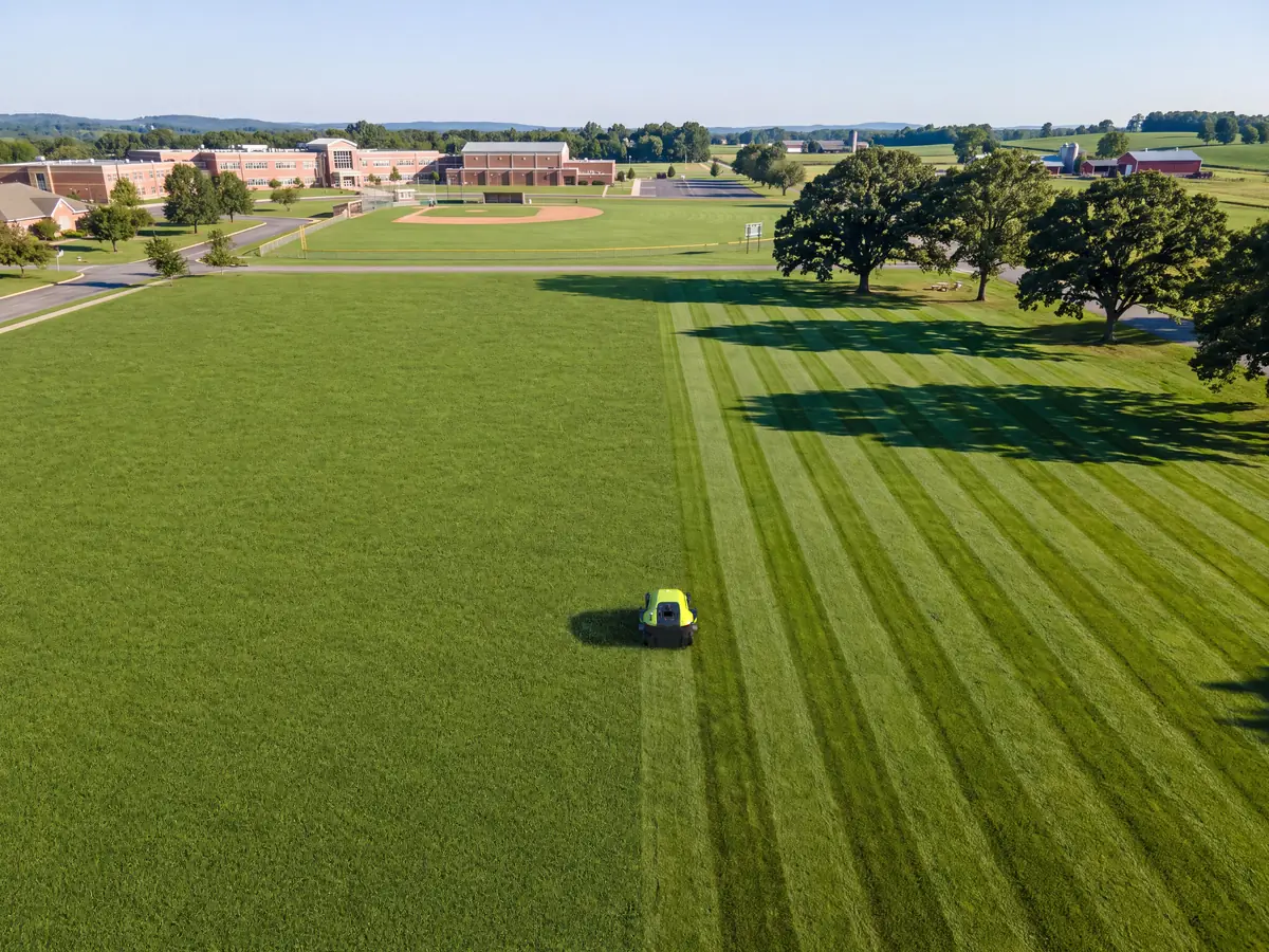 The PUDU GT5 mowing a large lawn in even stripes