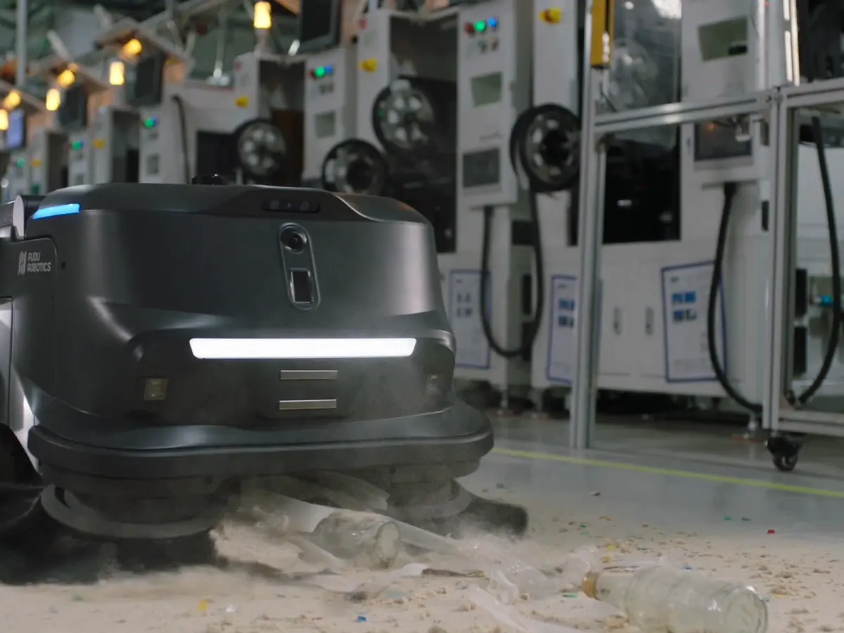 The PUDU MT1 picking up debris on a factory floor
