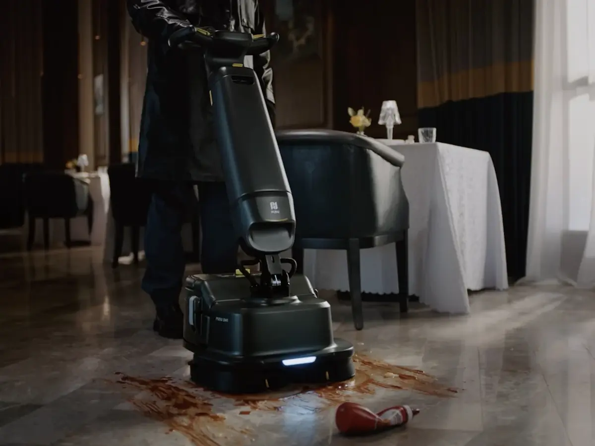 An operator scrubbing a restaurant floor with the PUDU SH1